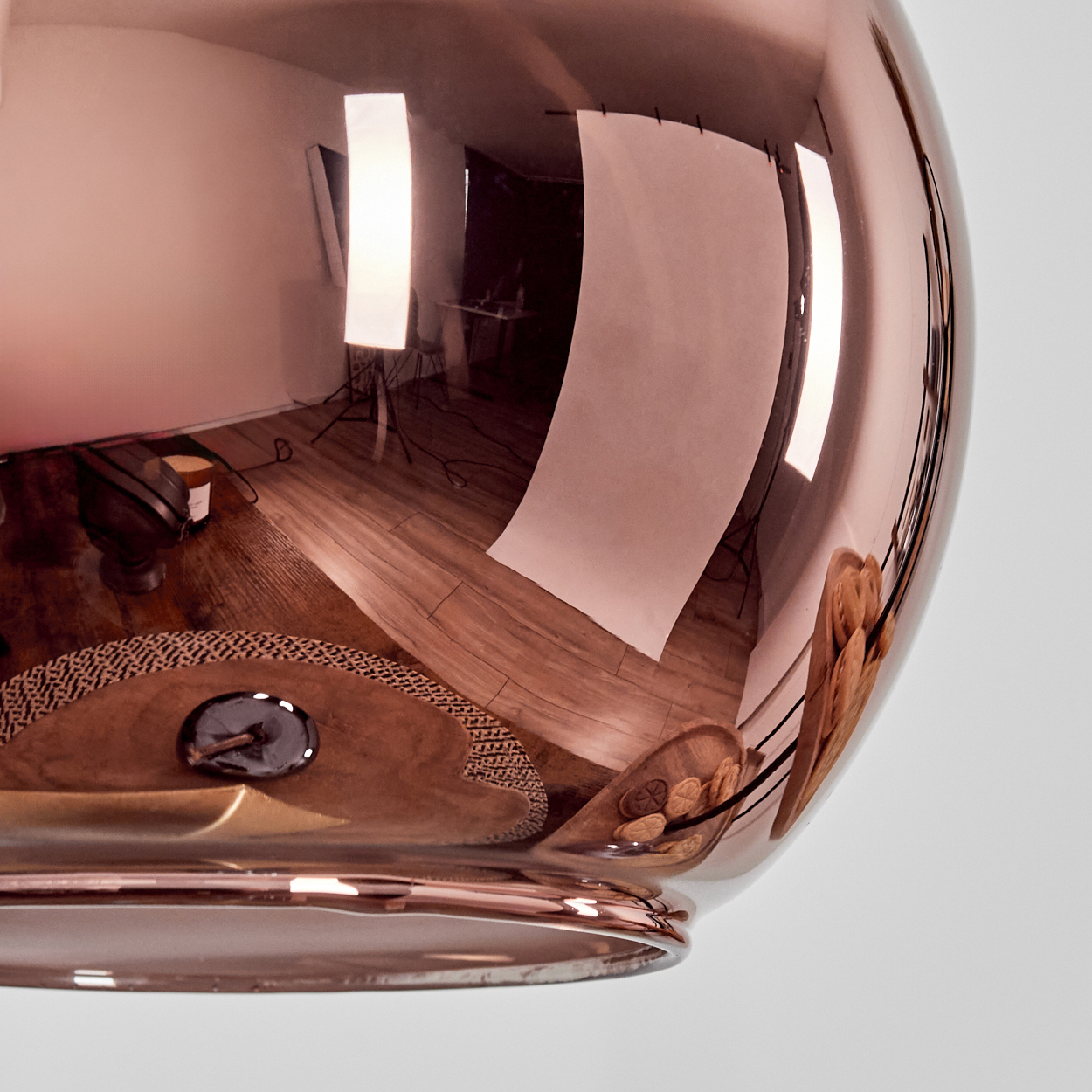 Eine kupferfarbene Kugel reflektiert ein Studio mit Lichtern und Kulissen.