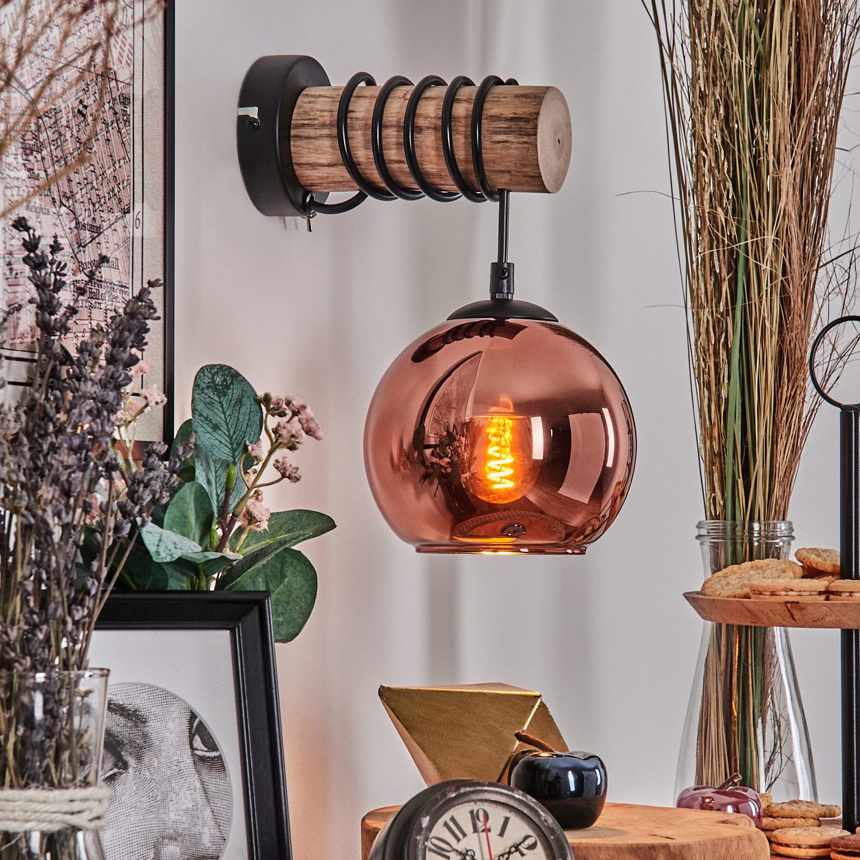 Kupferfarbene Pendelleuchte mit Glühbirne, Holz und Metall. Dekorationen im Hintergrund.