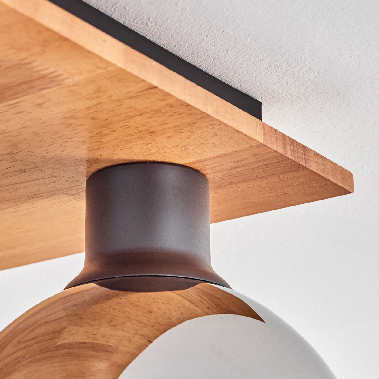 Holzregal mit schwarzem Rand und dunklem Lampenschirm im Detail.