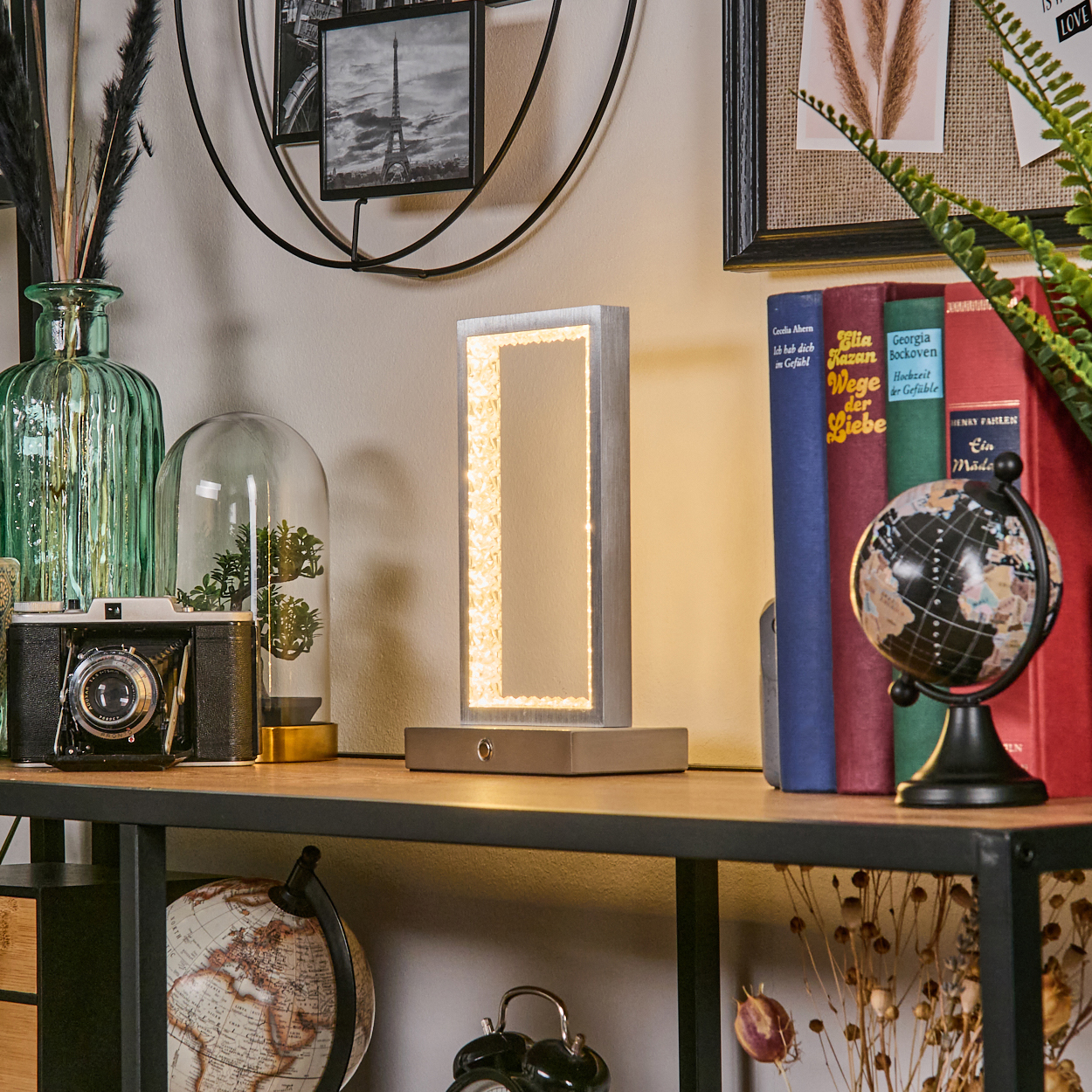 Ein stilvolles Regal mit Lampe, Büchern, einer Kamera und einer grünen Vase.