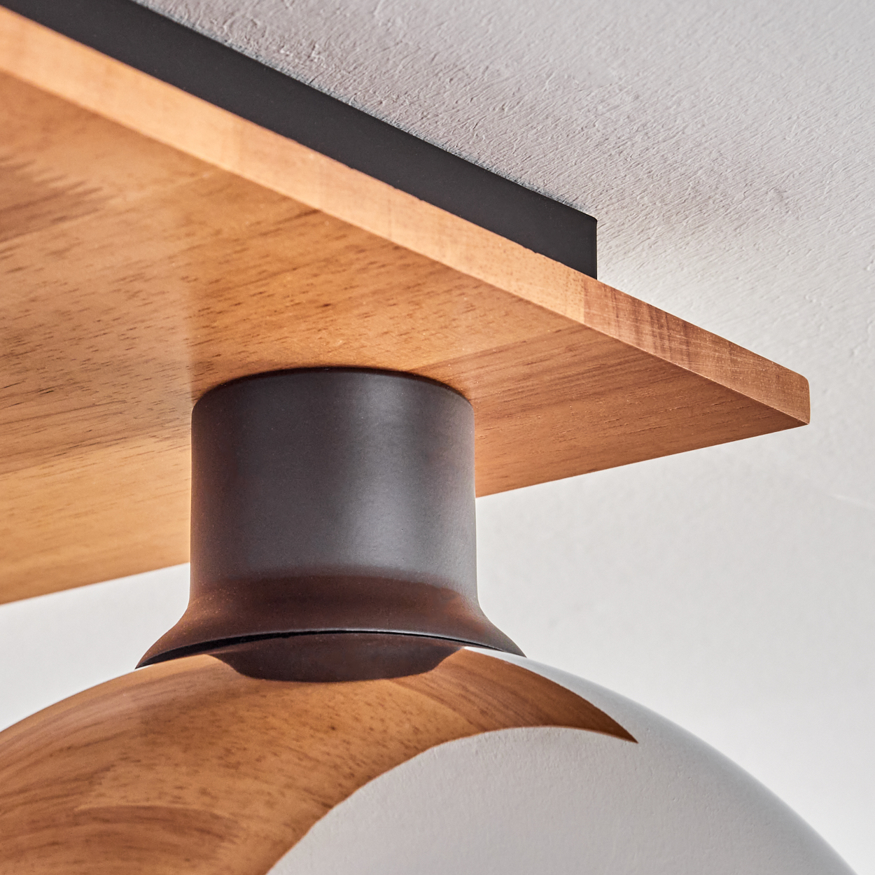 Holzdecke mit dunkler Halterung und weißer Lampe.