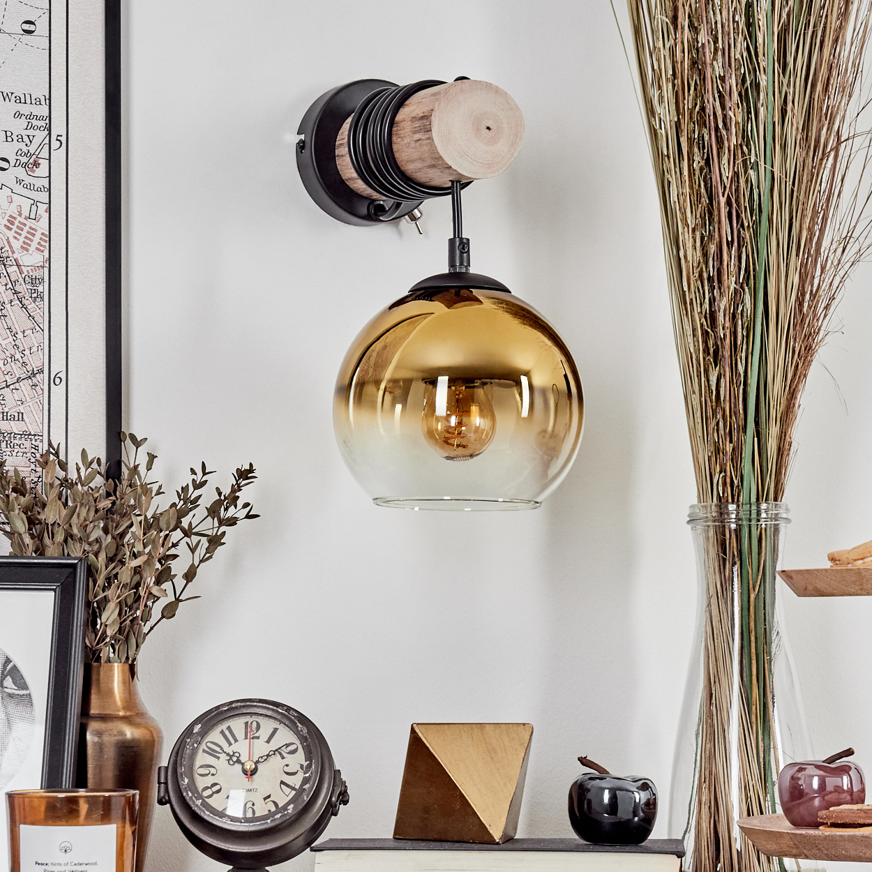 Eine Wandlampe mit bernsteinfarbenem Glasschirm hängt über einem Regal mit Dekorationen.