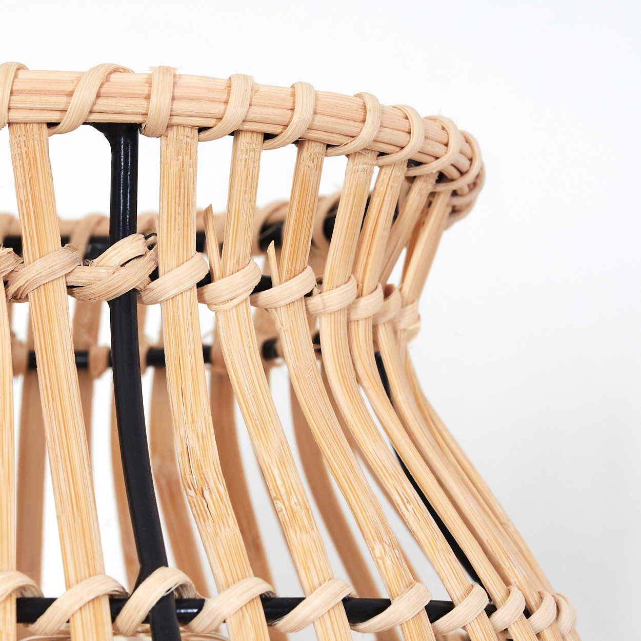 Nahaufnahme eines Korbes aus hellem Rattan mit schwarzen Stützen.