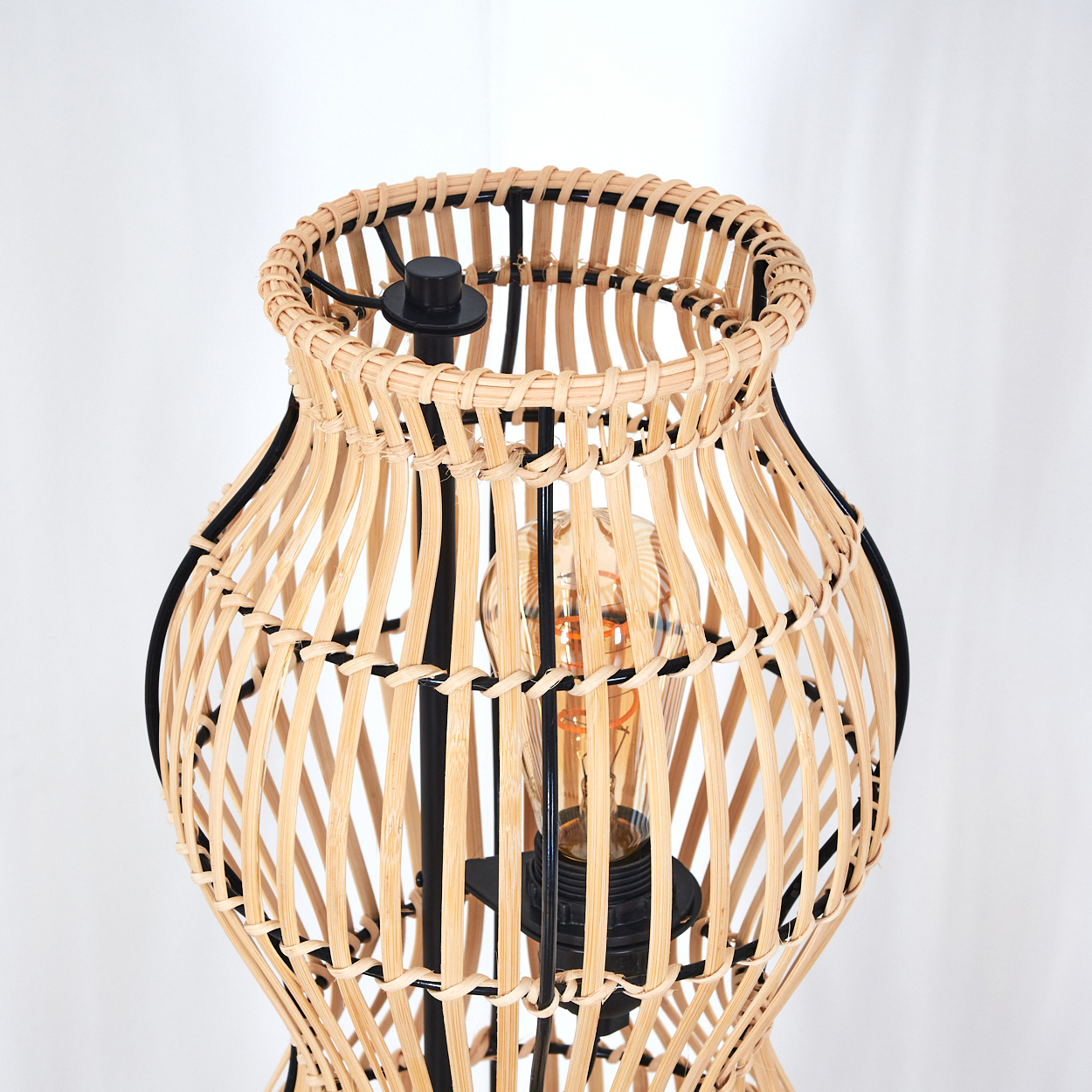 Eine Lampe mit einem Korbflecht-Schirm und sichtbarer Glühbirne.