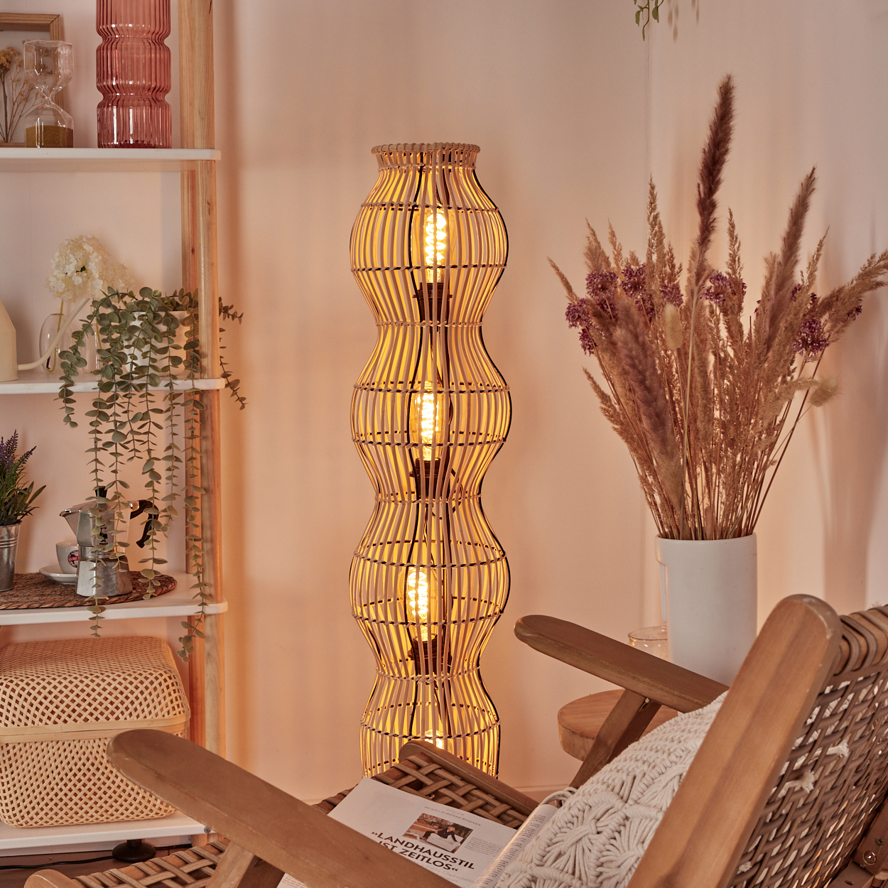 Ein Stehlampe aus Rattan mit Glühbirnen leuchtet neben zwei Holzstühlen.