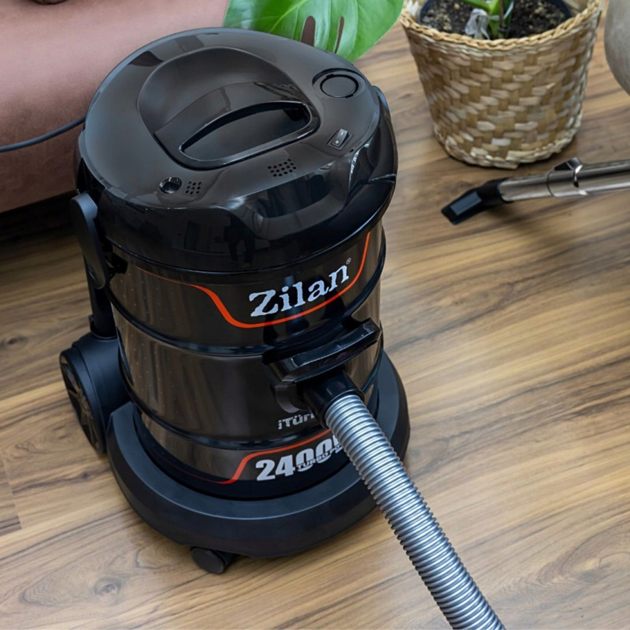Czarny odkurzacz Zilan z wężem na drewnianej podłodze. Widok z góry.