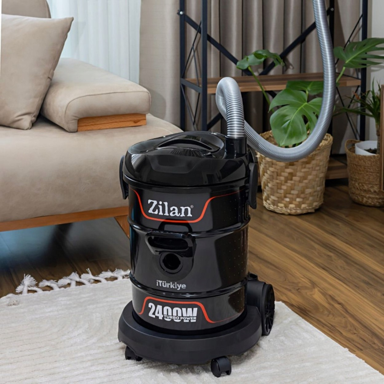 Czarny odkurzacz Zilan z czerwonymi akcentami stoi na dywanie.