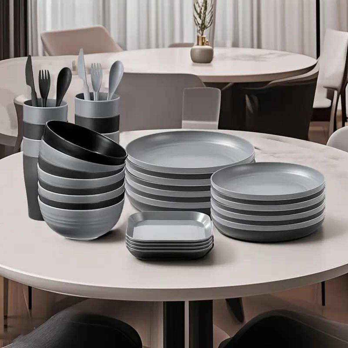 Graue und schwarze Teller, Schüsseln und Besteck auf einem Tisch.