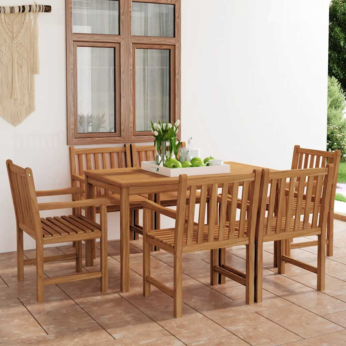 Un tavolo di legno con sedie si trova su un patio piastrellato davanti a una finestra.