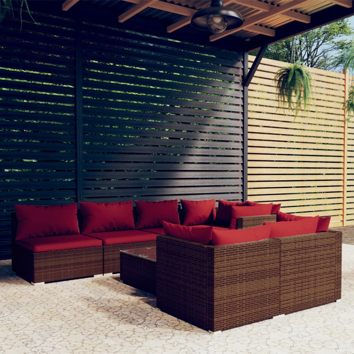 Divani in rattan marrone con cuscini rossi sotto una tettoia su un patio.