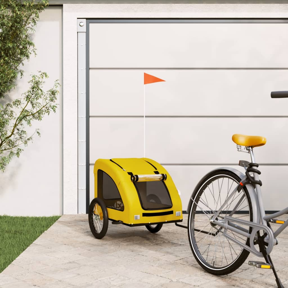 Ein gelber Fahrradanhänger mit orangefarbener Flagge neben einem grauen Fahrrad.
