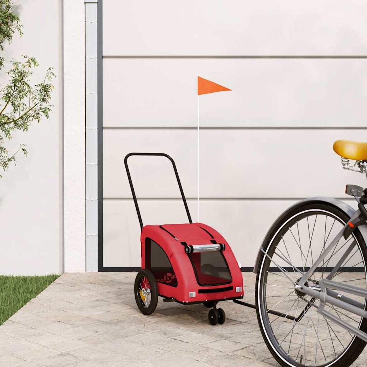 Ein roter Fahrradanhänger mit einem orangefarbenen Fähnchen steht neben einem Fahrrad.