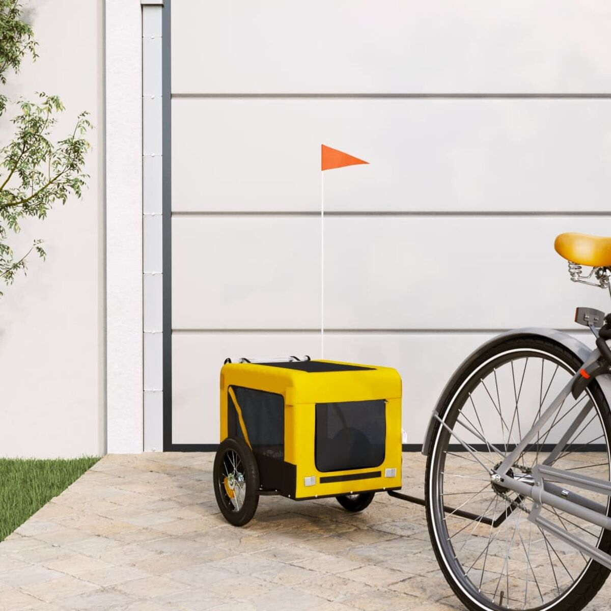 Ein gelber Fahrradanhänger mit orangefarbener Fahne steht neben einem Fahrrad.