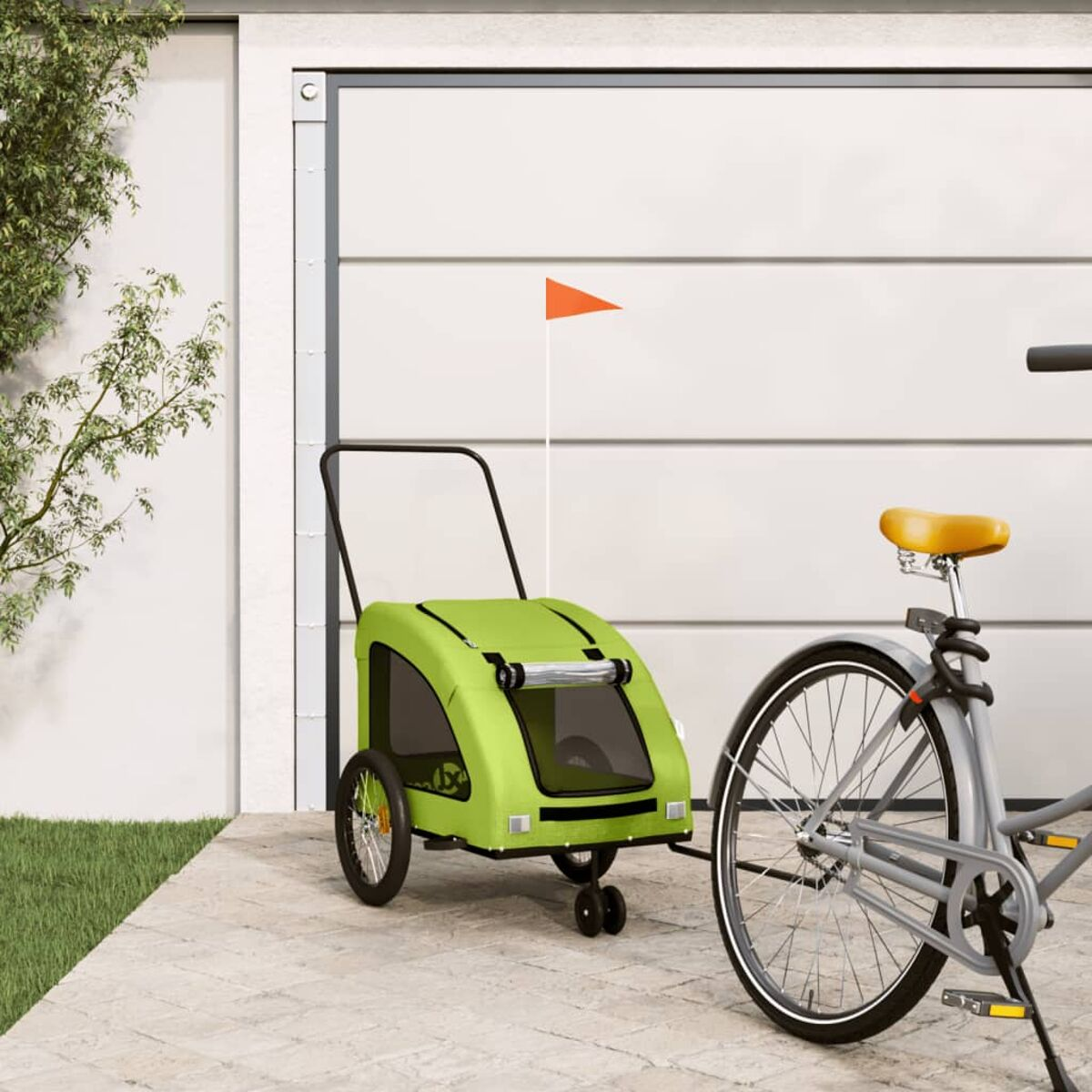 Ein grüner Fahrradanhänger mit orangefarbener Fahne steht neben einem Fahrrad.