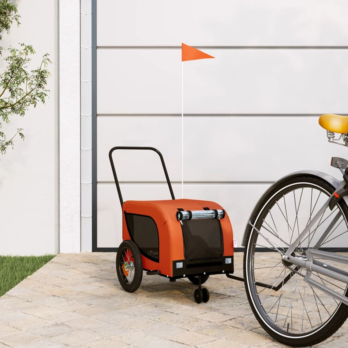Ein orangefarbener Fahrradanhänger mit einem Fähnchen steht neben einem Fahrrad.