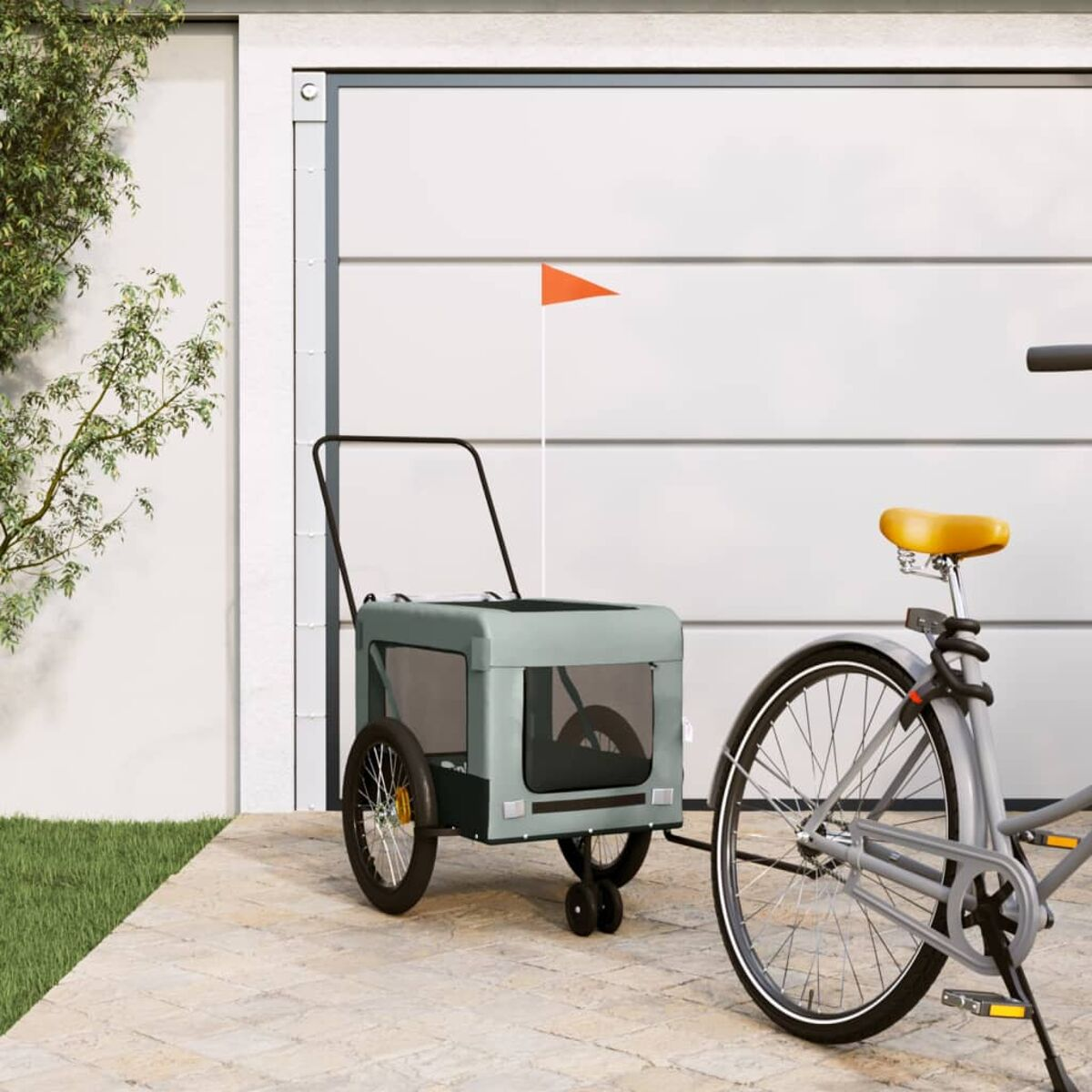Fahrradanhänger mit zwei Rädern und einer orangefarbenen Fahne, neben einem Fahrrad.