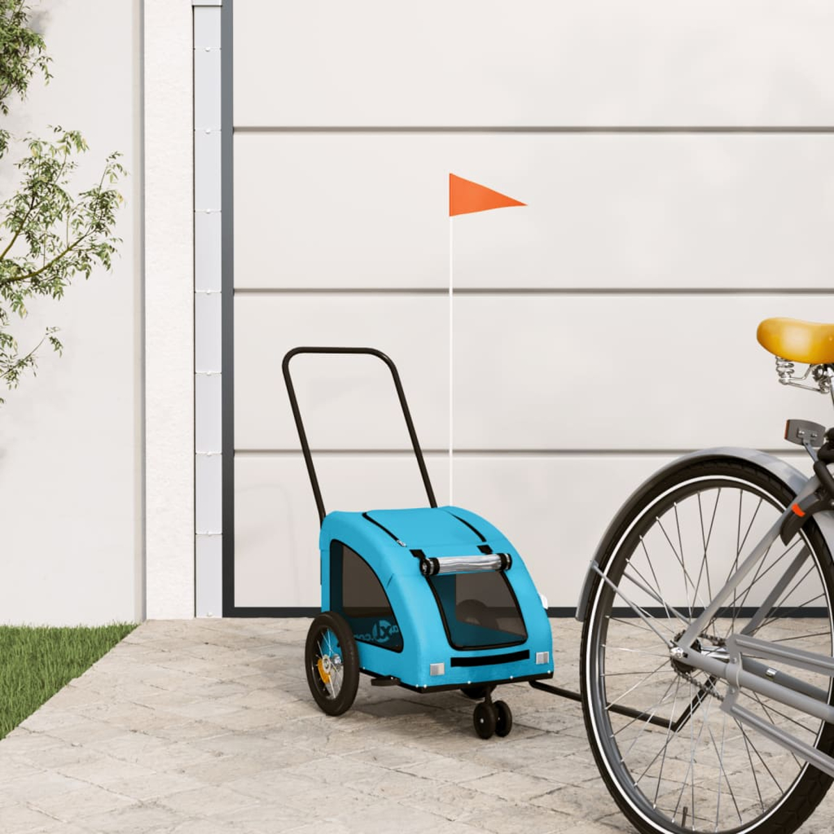 Ein hellblaues Fahrradanhänger mit orangem Fähnchen steht neben einem Fahrrad.
