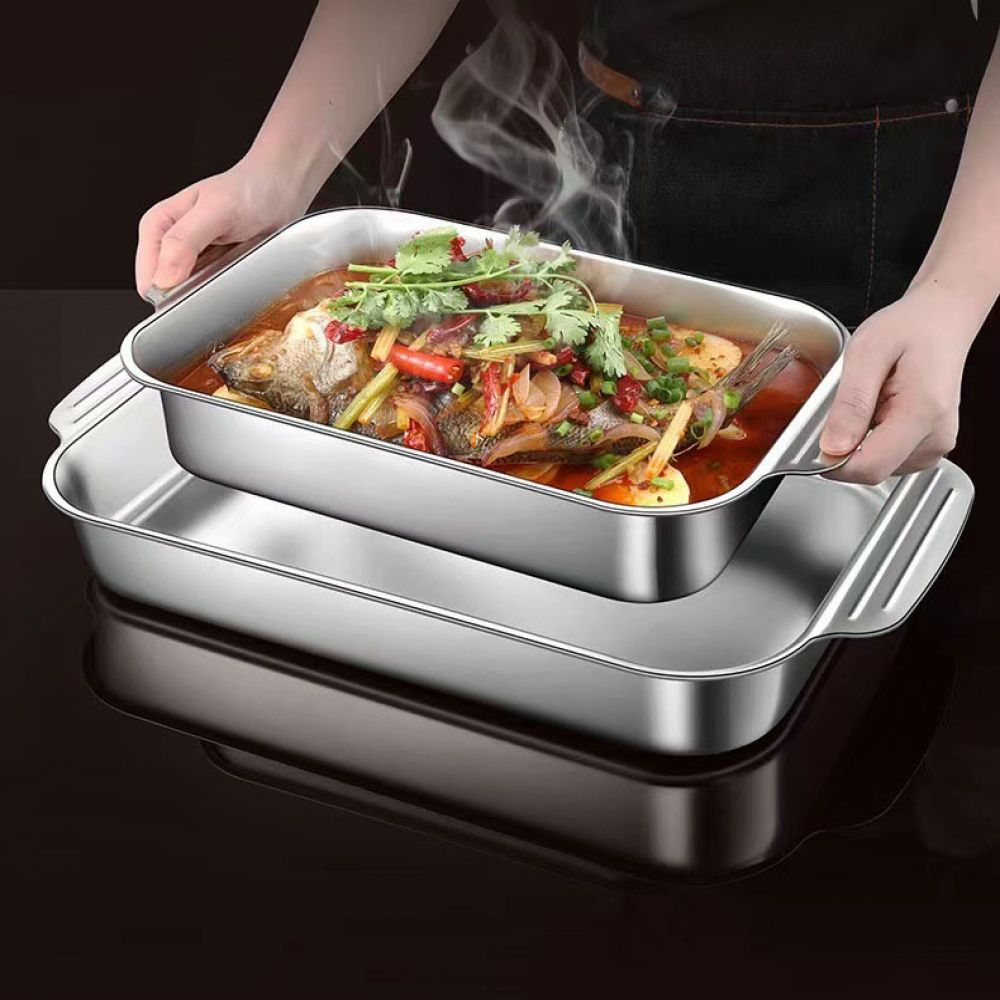 Hände halten eine dampfende Metallbackform mit einem ganzen Fisch und Gemüse.