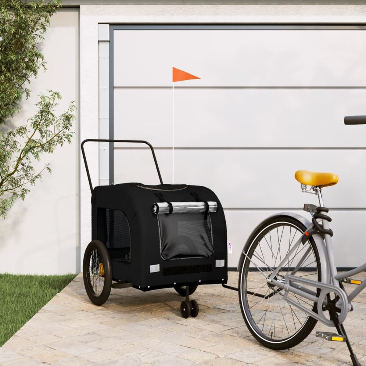 Ein schwarzer Fahrradanhänger mit orangefarbener Fahne neben einem Fahrrad.