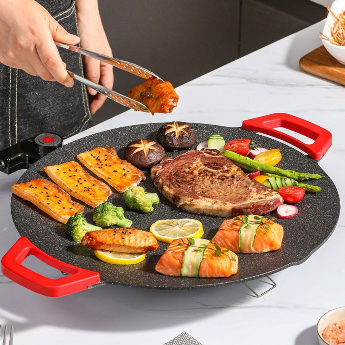 Grillplatte mit Steak, Lachs, Hähnchenflügeln, Gemüse und Pilzen.