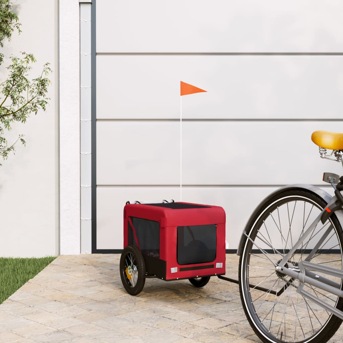 Ein roter Fahrradanhänger mit oranger Flagge vor einer Garage.