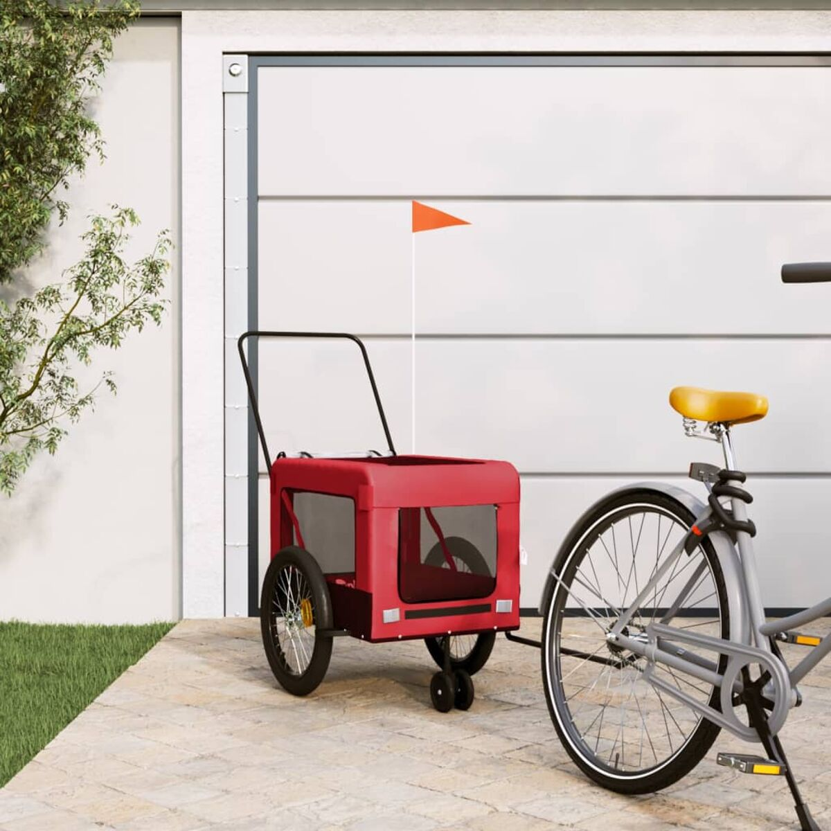 Ein roter Fahrradanhänger mit orangefarbener Fahne steht neben einem grauen Fahrrad.