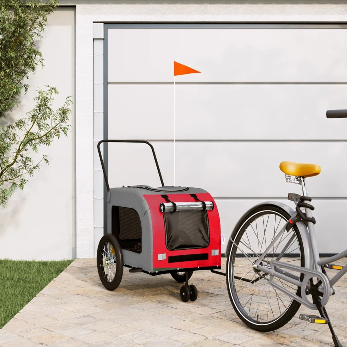 Ein roter und grauer Fahrradanhänger mit orangefarbener Flagge neben einem Fahrrad.
