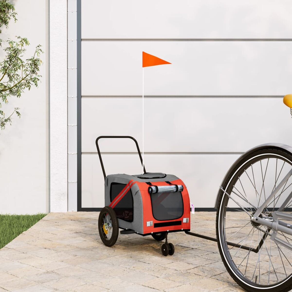 Ein orangefarbener Fahrradanhänger für Haustiere mit einem Fähnchen steht neben einem Fahrrad.