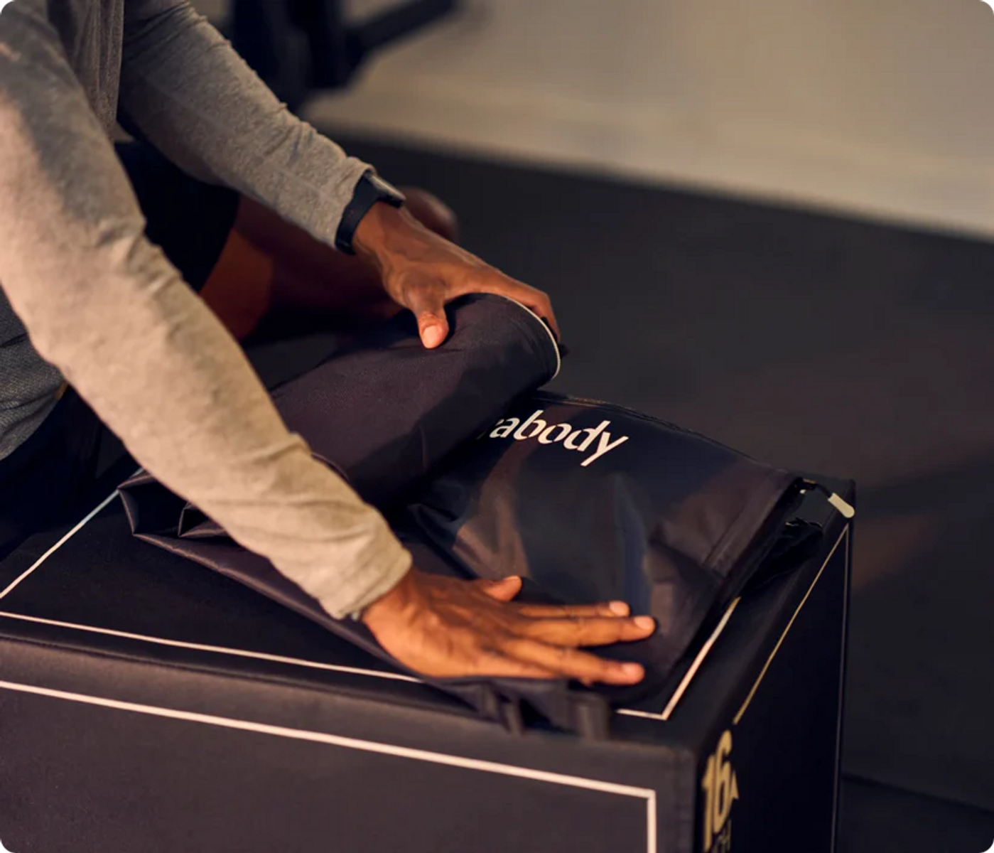 Persona che piega una borsa nera con logo 'abody' su una scatola nera.