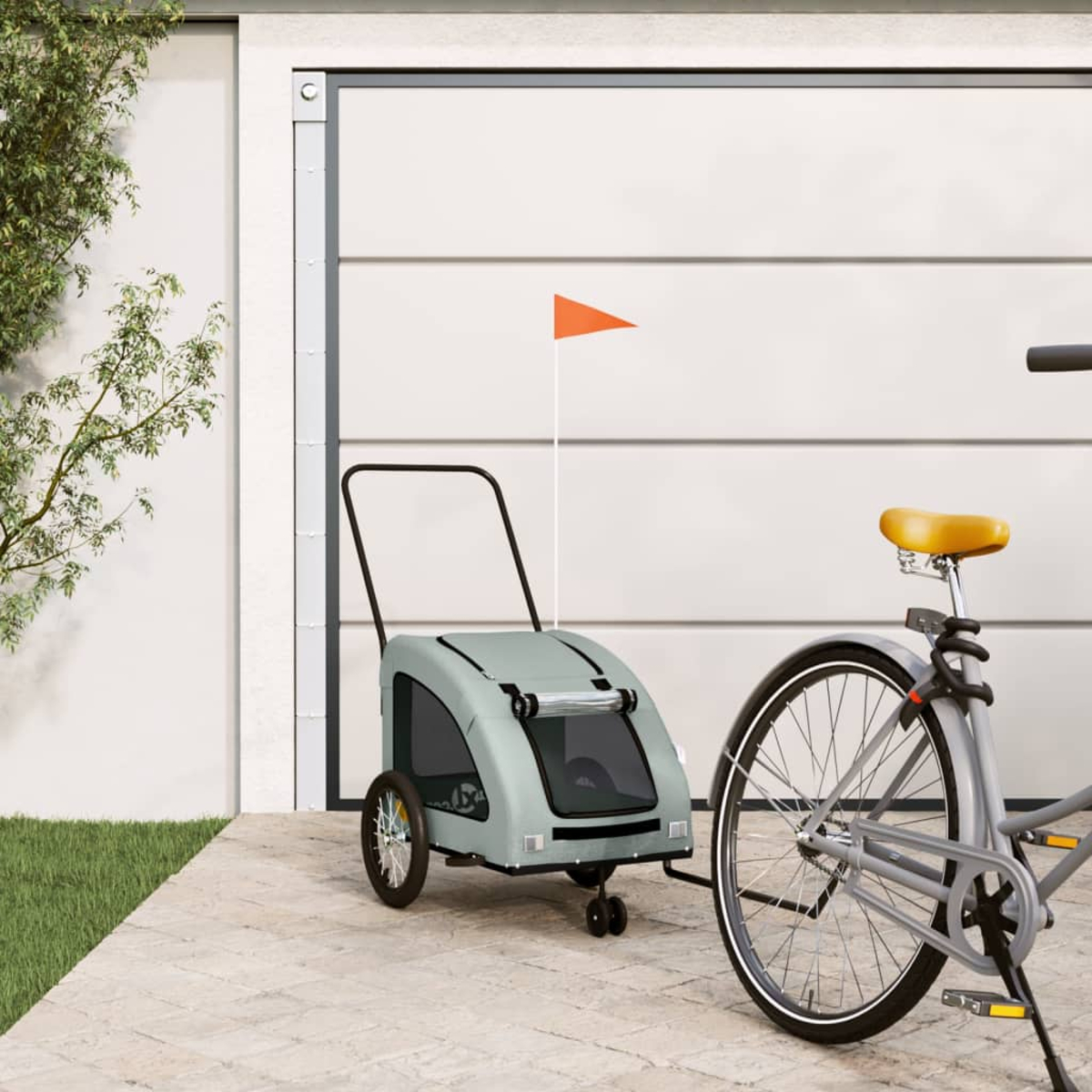 Ein hellgrüner Hundanhänger mit orangefarbener Flagge ist an einem grauen Fahrrad befestigt.