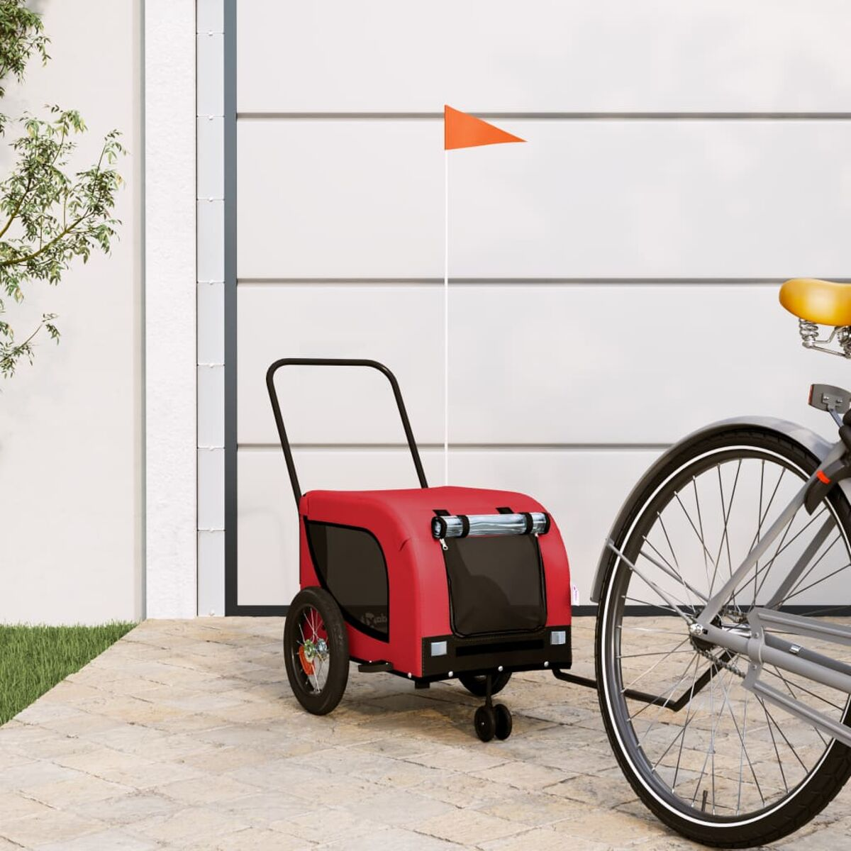 Ein roter Fahrradanhänger mit orangefarbener Flagge steht neben einem Fahrrad.