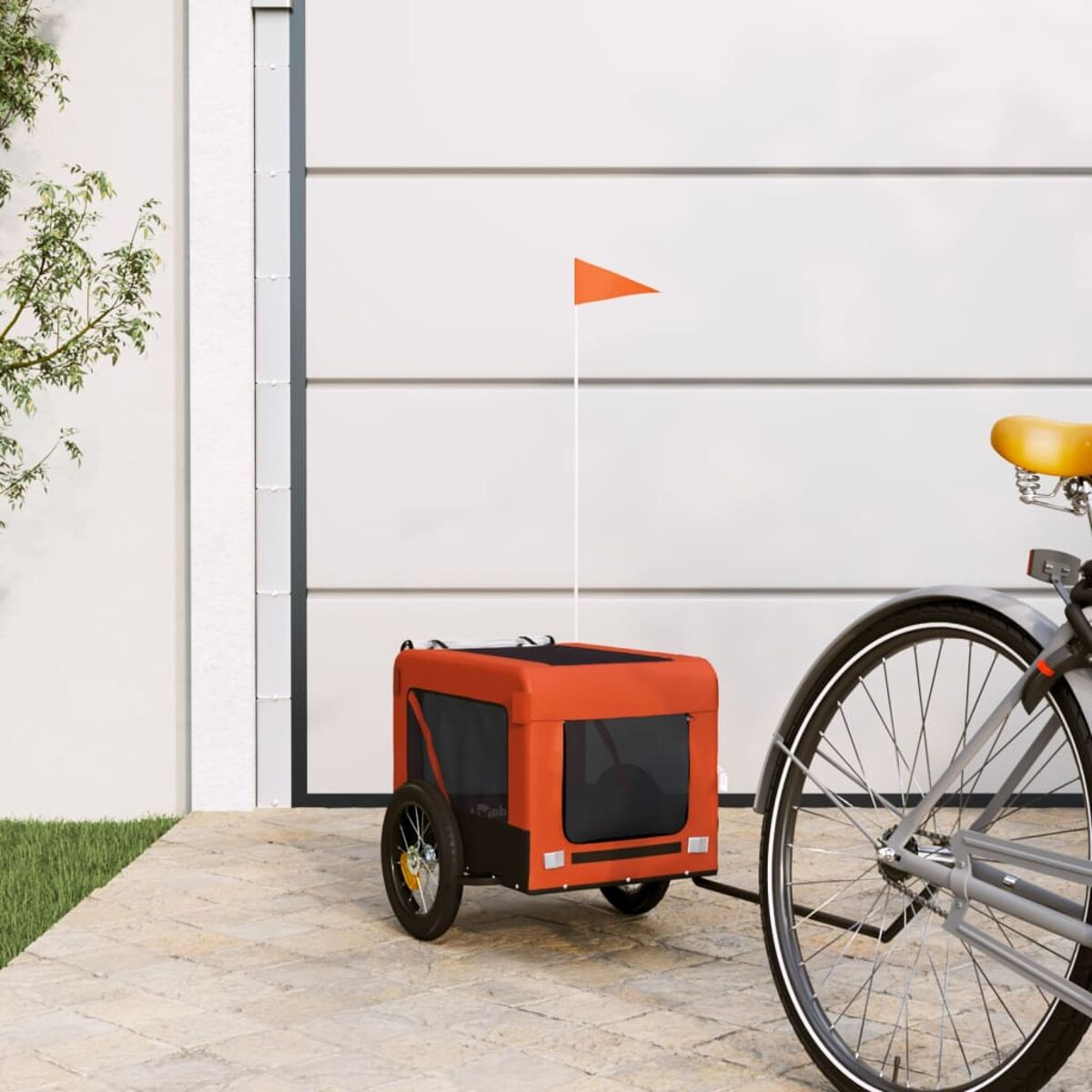 Orange Fahrradanhänger mit Flagge neben einem Fahrrad vor einer Garage.