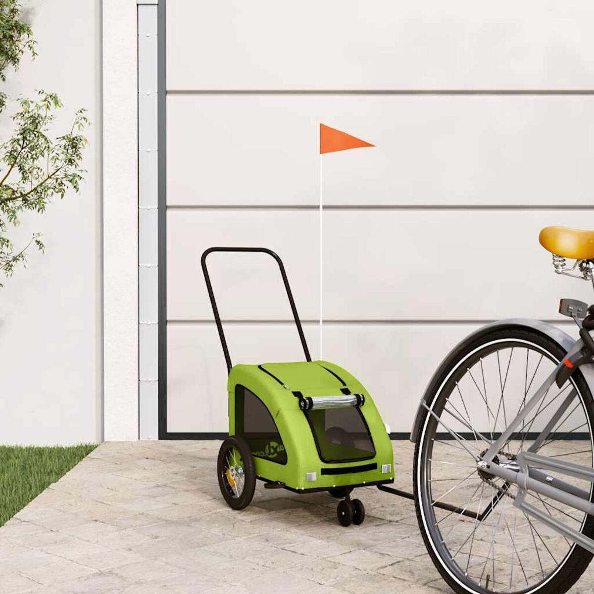 Ein grüner Fahrradanhänger mit orangefarbener Fahne steht neben einem Fahrrad.