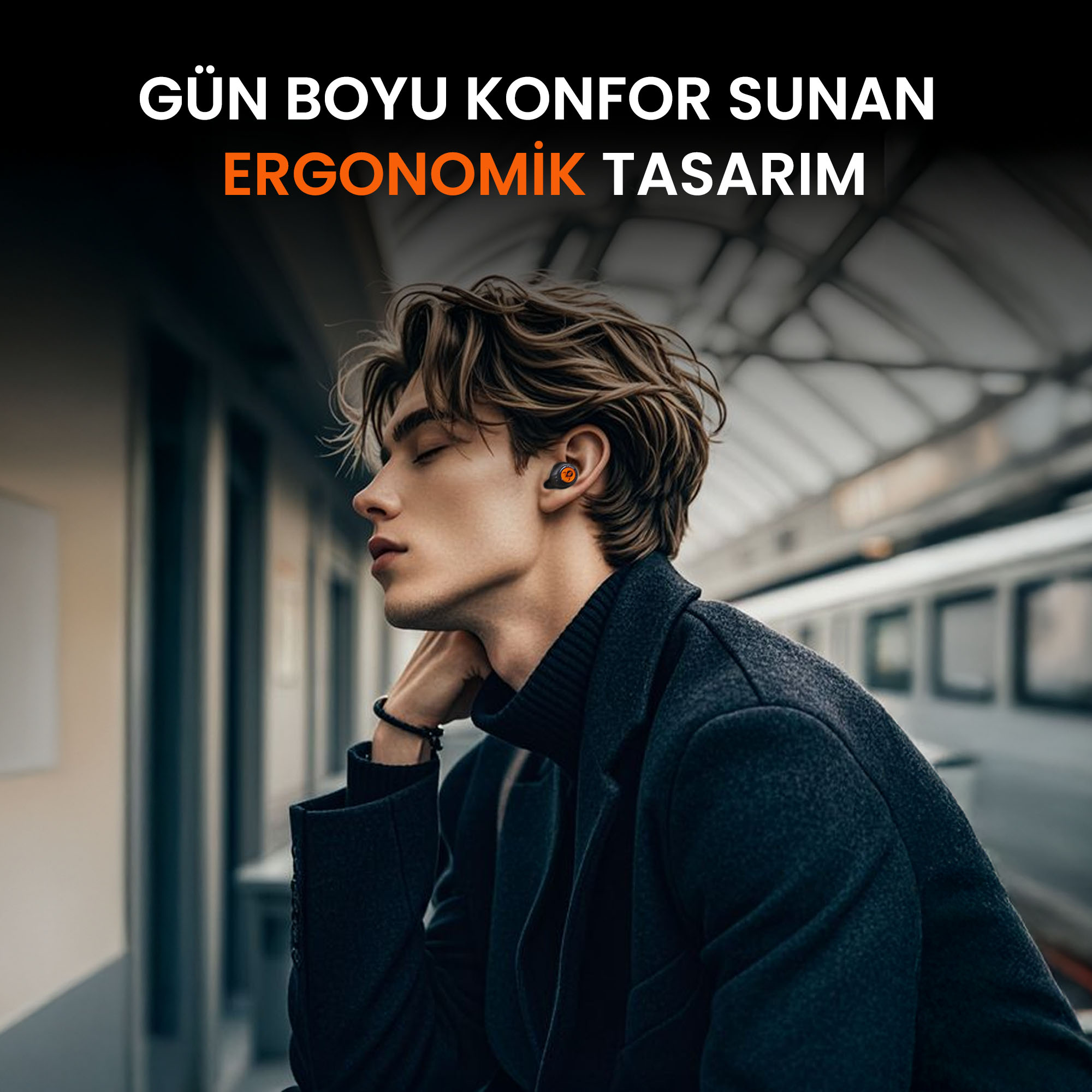 Kulaklıklı bir adam koyu renk bir ceketle tren platformunda oturuyor.