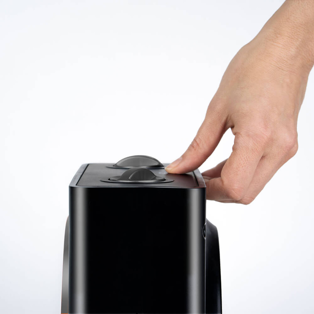 Dłoń naciska przycisk na czarnym urządzeniu.