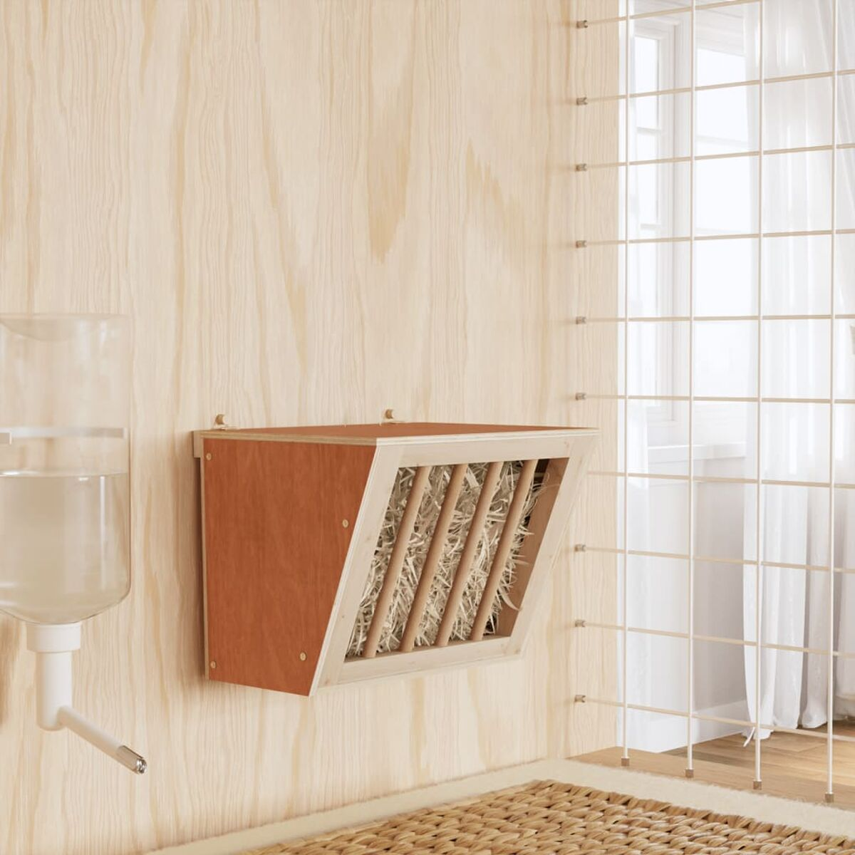 Ein hölzerner Heuraufe und ein Wasserspender an einer Holzwand.