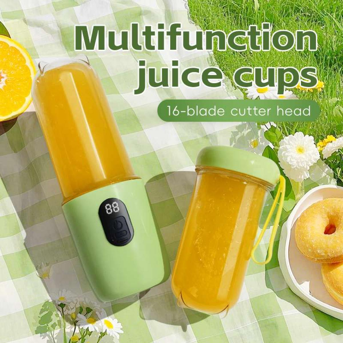 Ein tragbarer Mixer, Saftbecher, Orangen, Donuts und Blumen auf karierter Decke.
