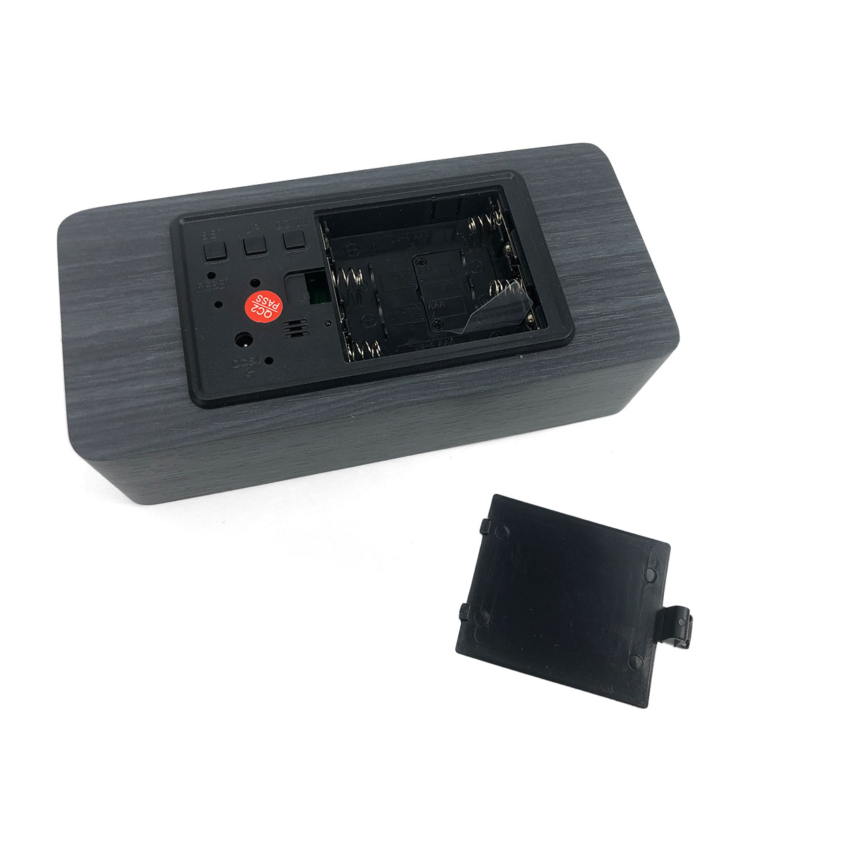 Ciemny zegar cyfrowy z otwartą komorą baterii, pokazującą gniazda.