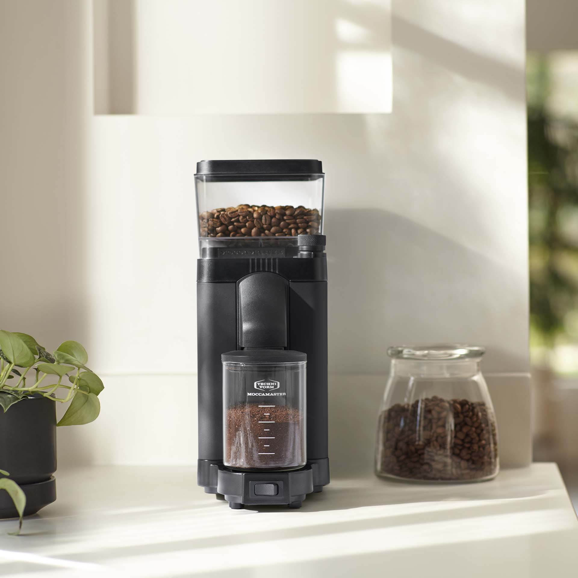 Ein schwarzer Kaffeemühlen-Stand mit Kaffeebohnen und gemahlenem Kaffee.