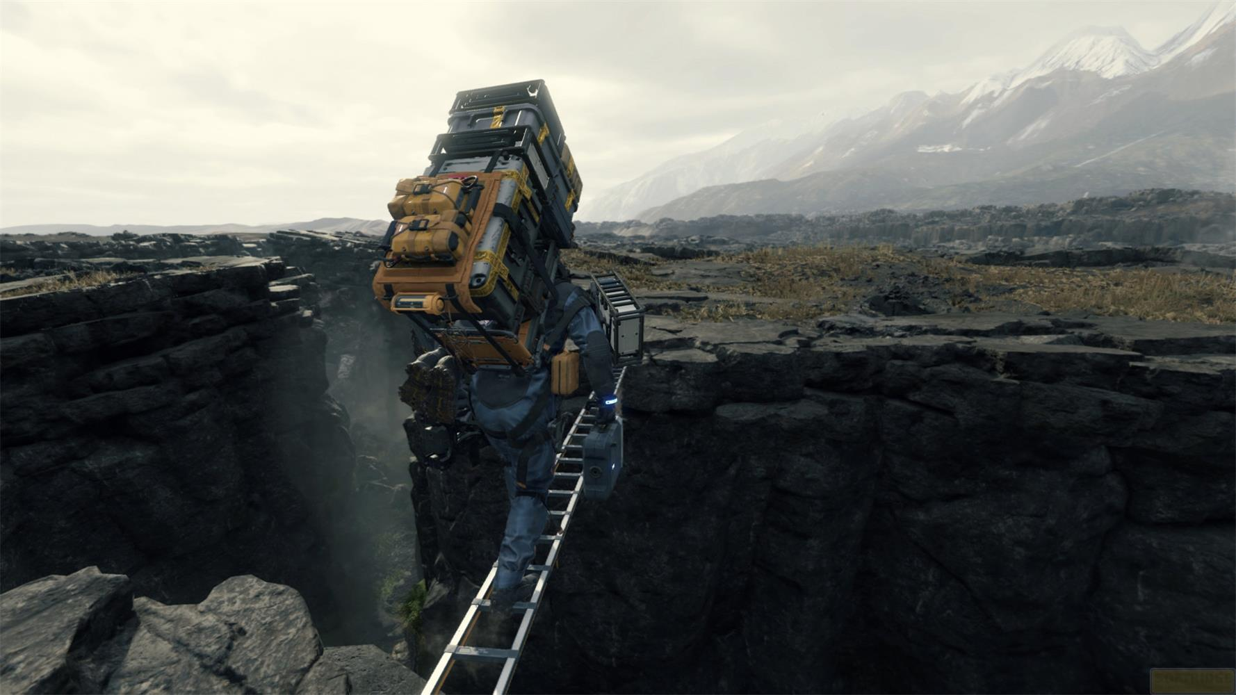 Une personne traverse un gouffre sur une échelle, chargée de fret. Montagnes au loin.