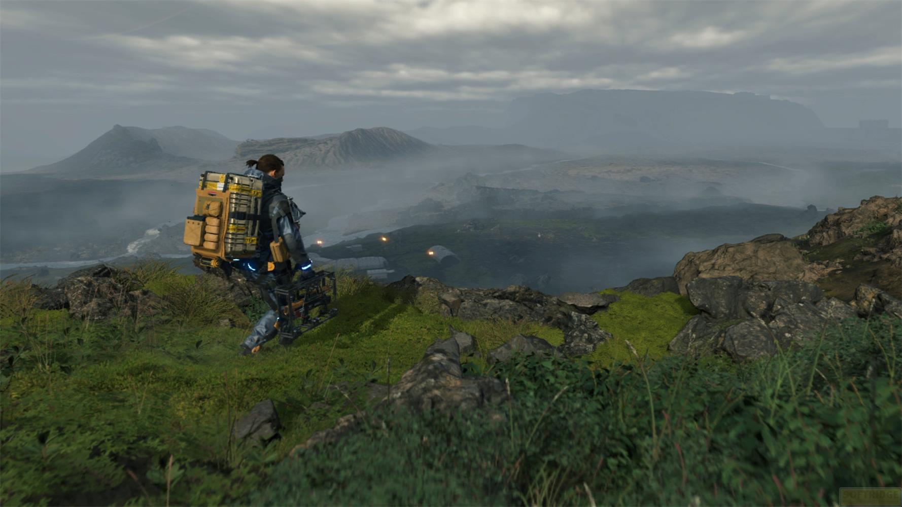 Une personne avec un sac à dos se tient sur une colline rocheuse surplombant un paysage brumeux.