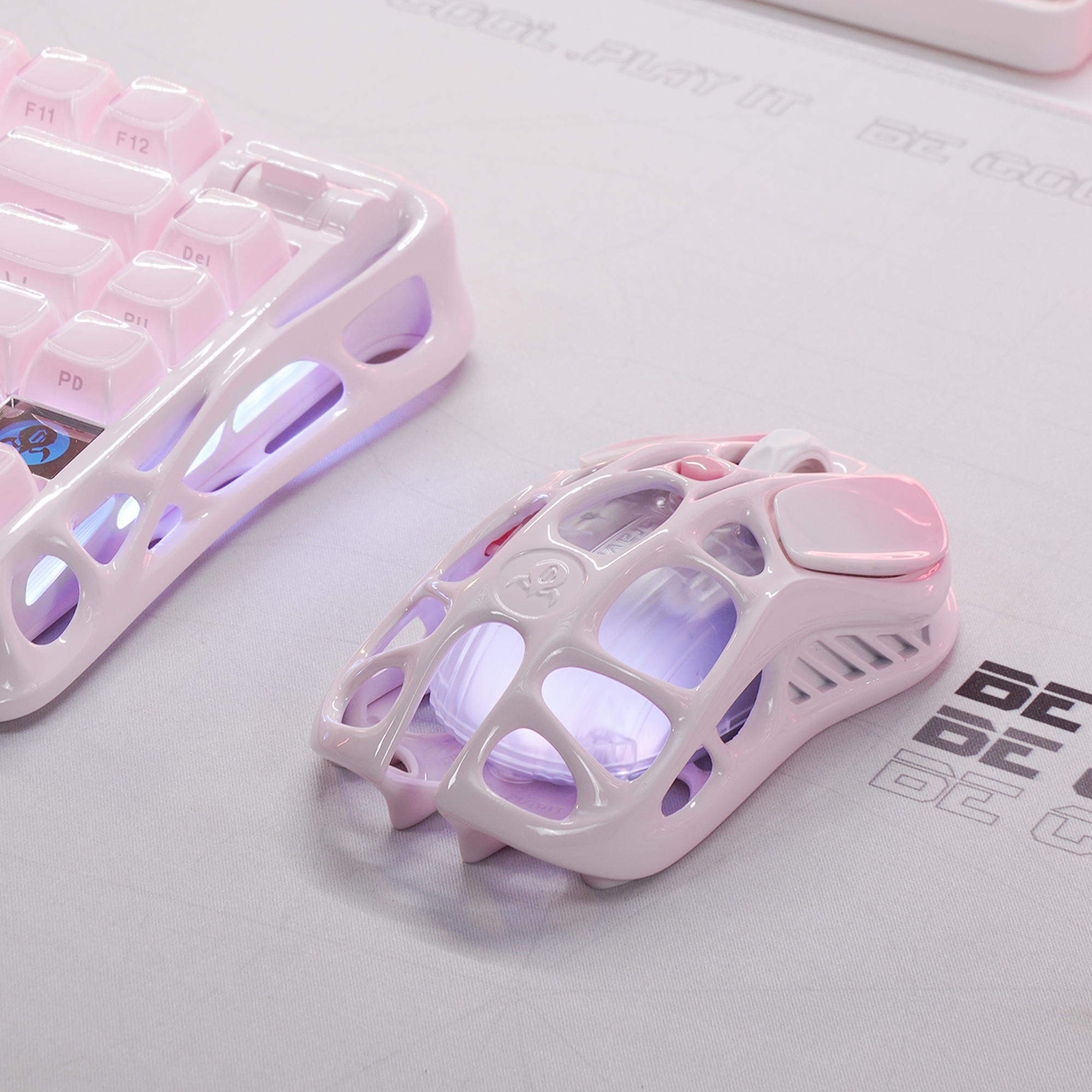 Una tastiera da gaming rosa e un mouse dal design aperto su un tappetino.