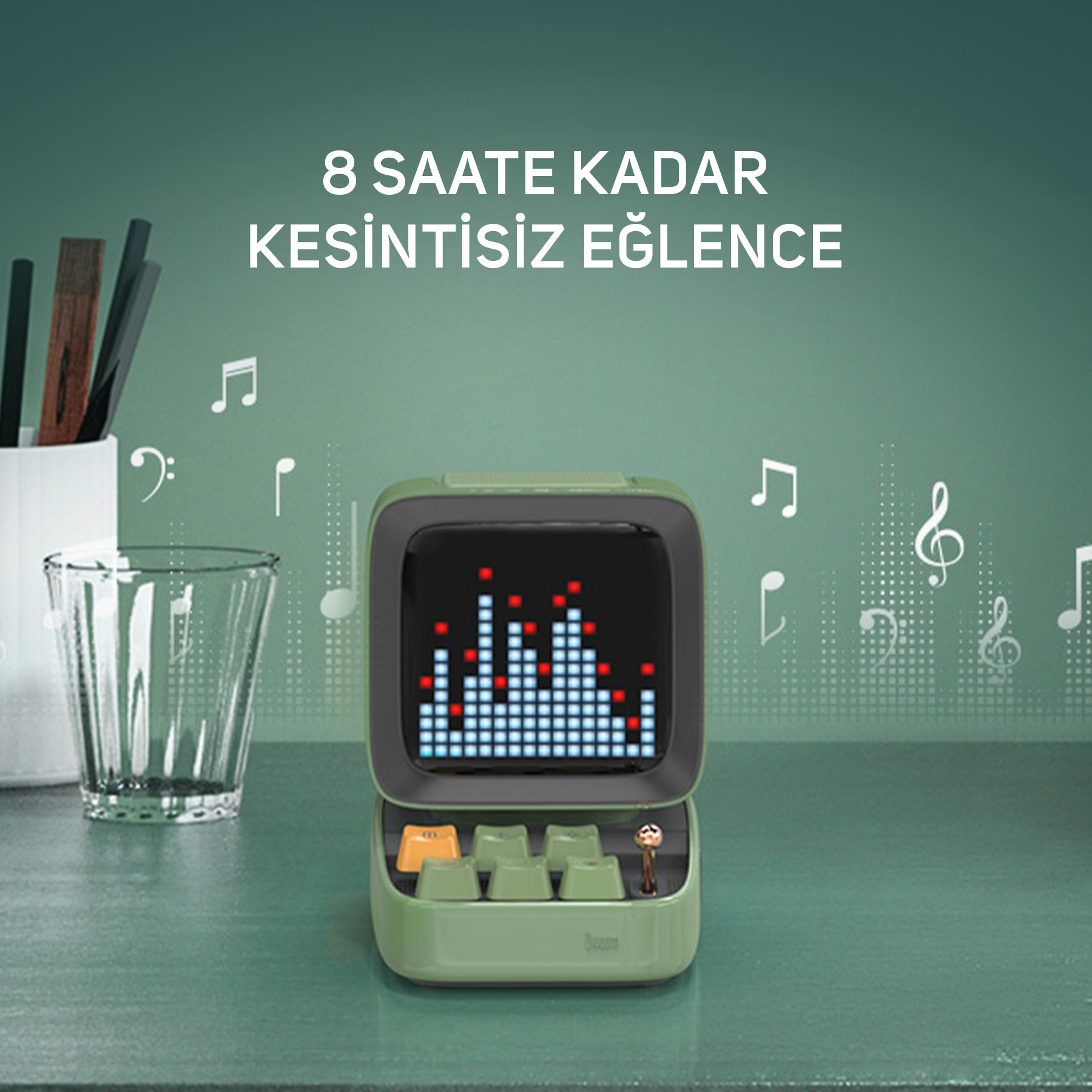 Yeşil hoparlör, ekolayzer ekranlı, yanında bardak ve kalemler.