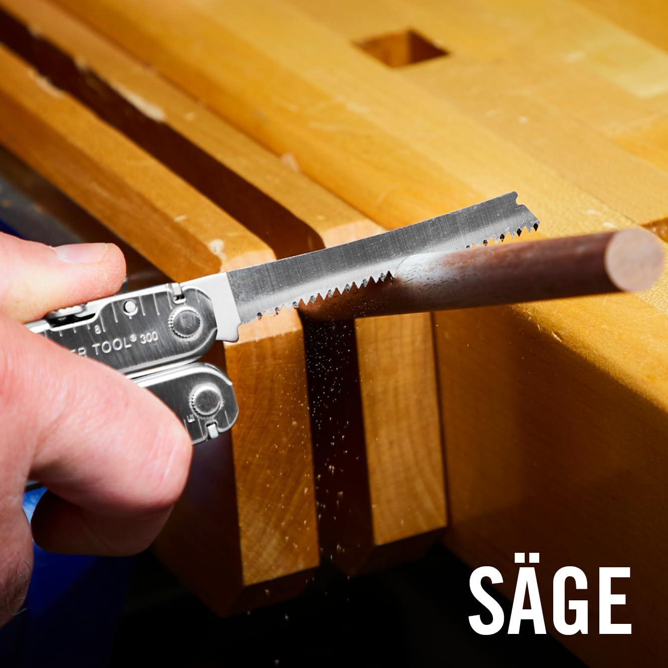 Eine Hand hält ein Multitool mit Sägeblatt, das Holz sägt.