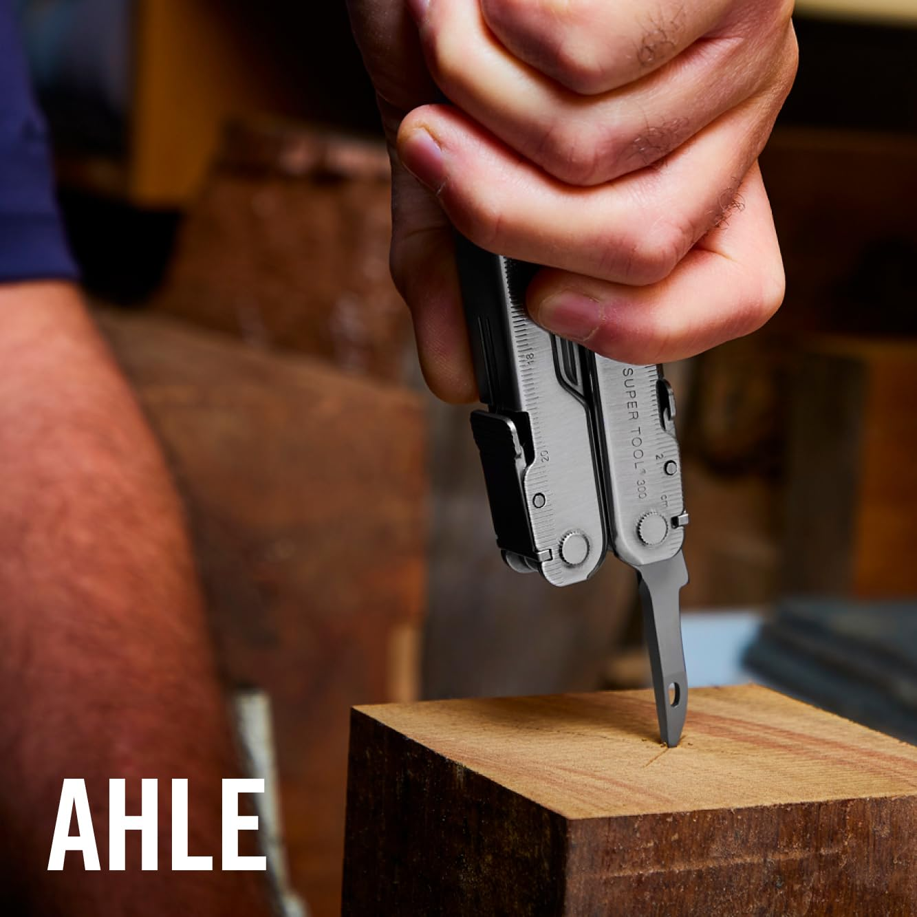 Eine Hand hält ein Multitool und benutzt die Klinge, um in Holz zu schneiden.