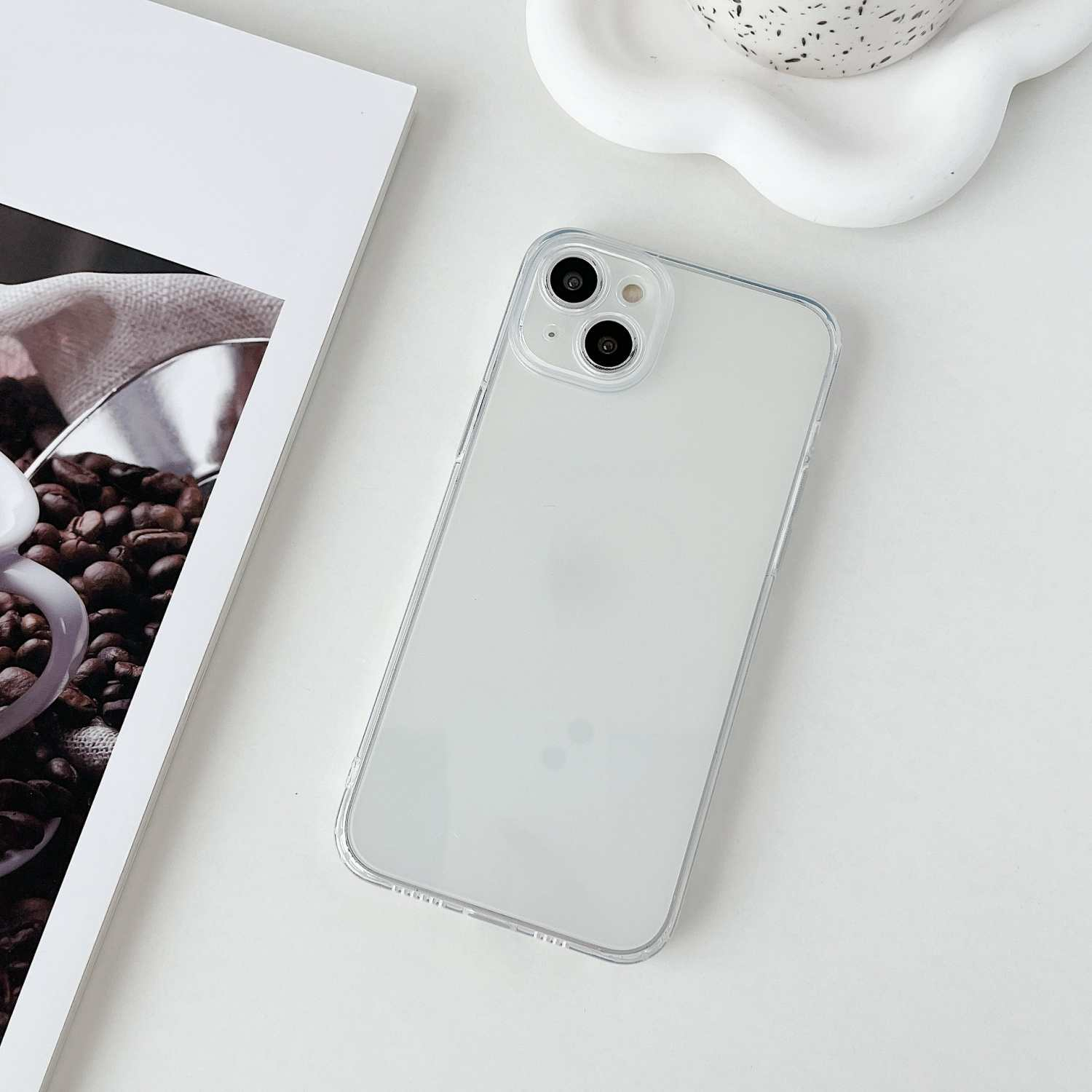 Ein durchsichtiges Handy mit zwei Kameras liegt auf einem weißen Tisch.