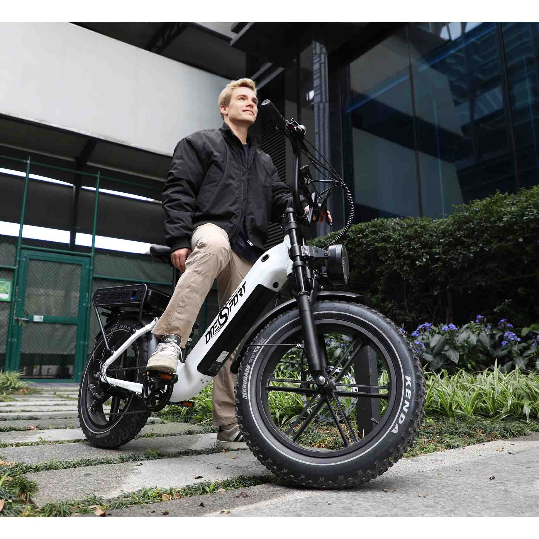 Ein Mann in schwarzer Jacke und Khaki-Hose sitzt auf einem weißen E-Bike im Freien.