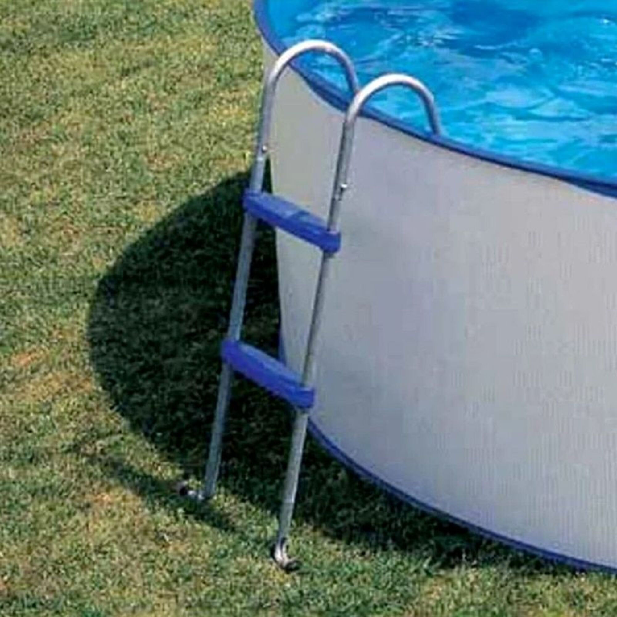 Una escalera junto a una piscina inflable sobre césped.