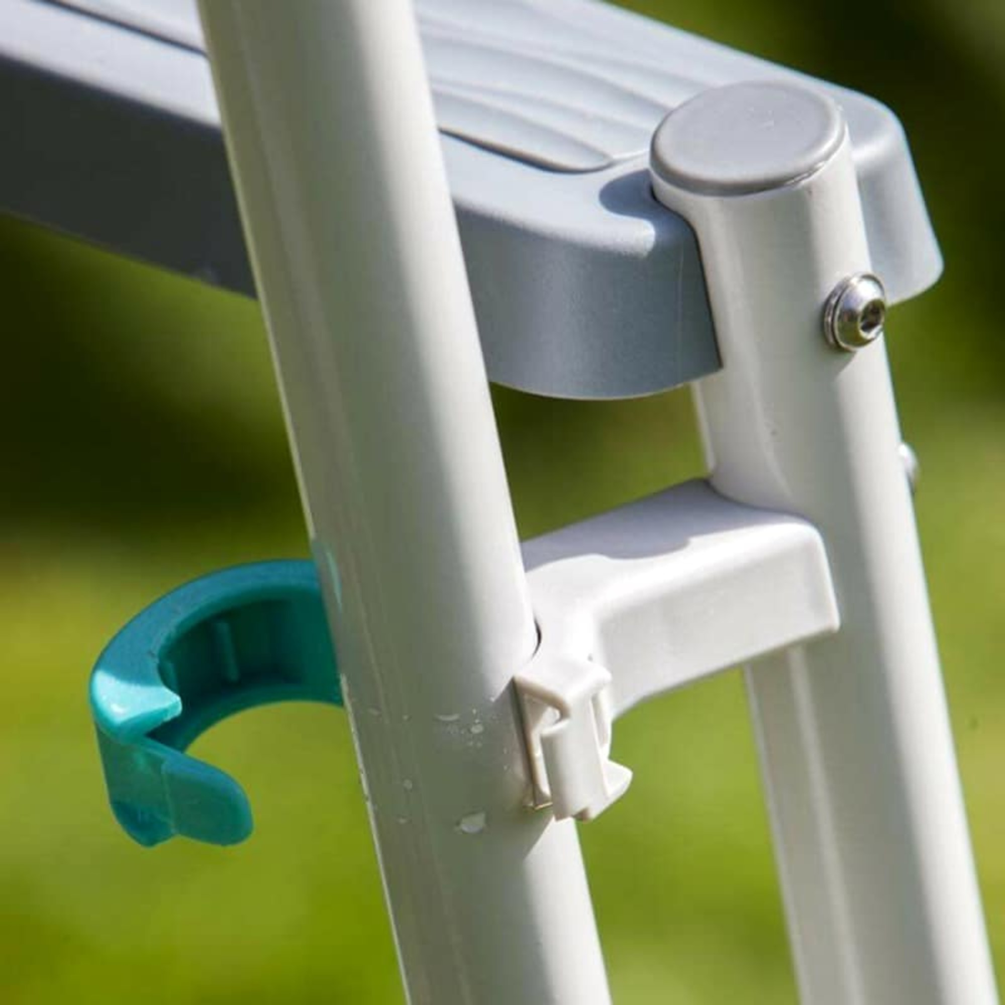 Primer plano de una escalera con gancho turquesa y partes de plástico grises.