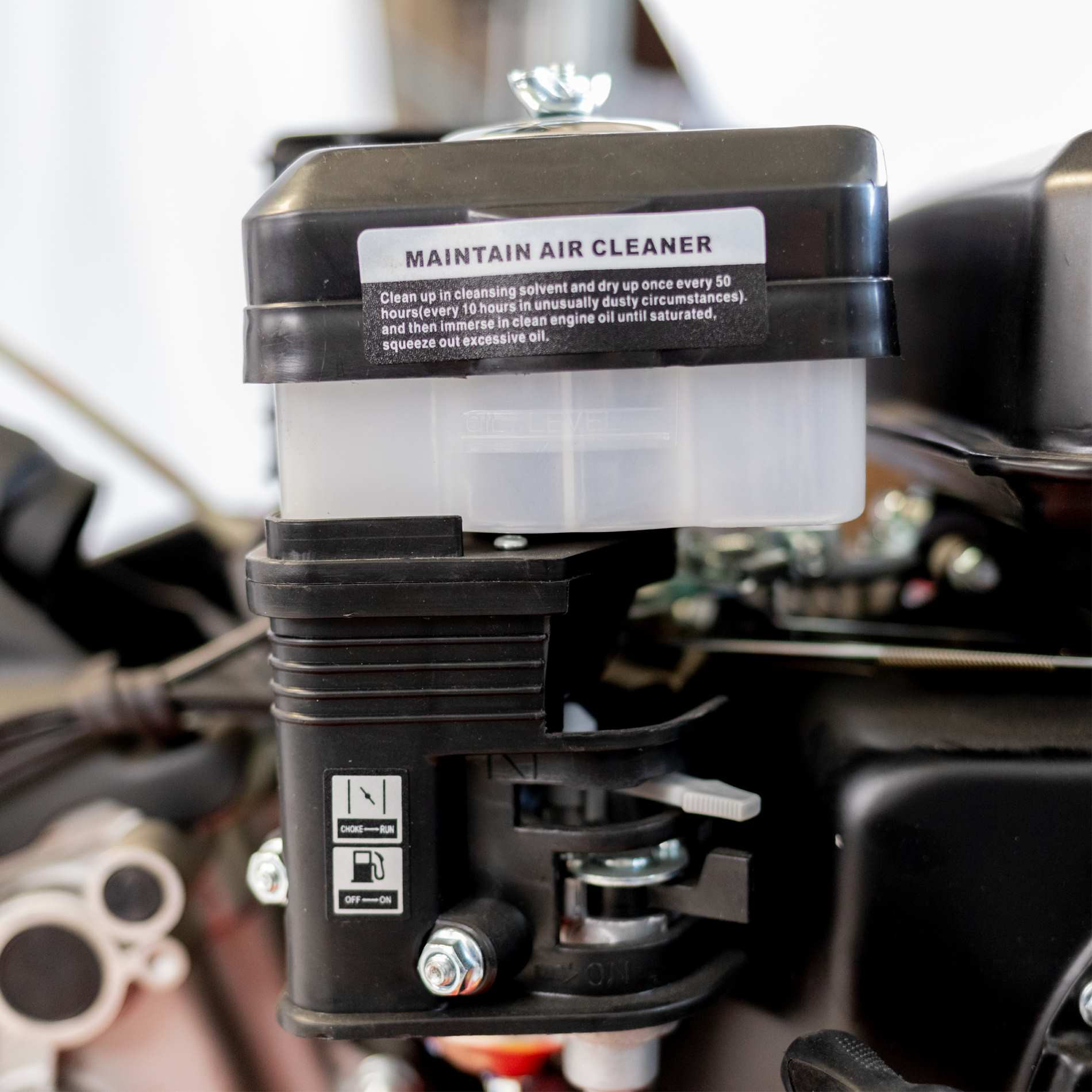 Czarna obudowa filtra powietrza z instrukcjami konserwacji i wskaźnikiem poziomu oleju.
